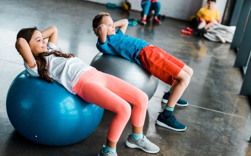 Kids doing abs exercise with fitness balls